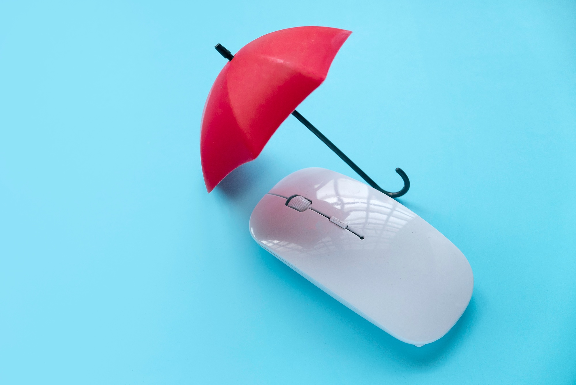 Computer and network security concept. Red umbrella over a computer mouse.
